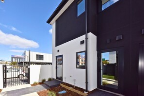 A modern building with a dark facade, a white section, and a gated entrance. - Relaxing Christchurch Base near the CBD (Christchurch)