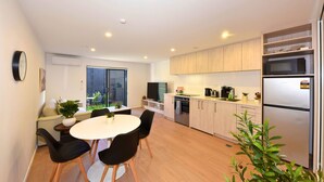 Una cucina moderna con zona pranzo, elettrodomestici integrati e una porta vetrata scorrevole su un balcone.