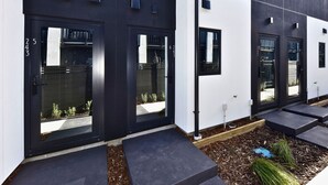 Un edificio moderno con due porte nere, numerate 25 e 26, e un muro bianco con una finestra.