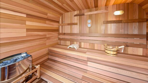 Una sauna in legno con panche, un riscaldatore per panche e un catino.