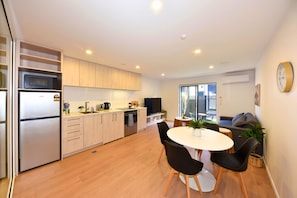 Eine moderne Küche mit Kühlschrank, Mikrowelle und Herd, ein Essbereich mit Tisch und Stühlen sowie ein Wohnbereich mit Sofa und Fernseher.