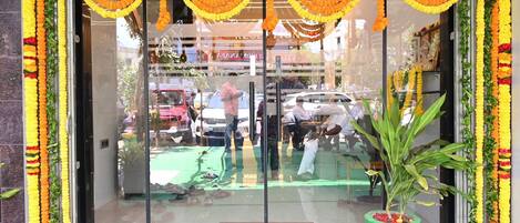 A hotel entrance with a glass door, a green mat, and a potted plant.