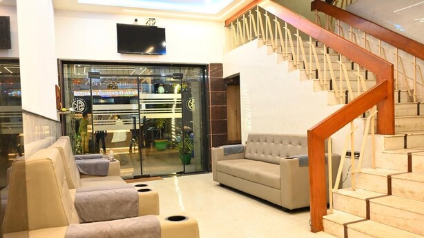 Un vestíbulo moderno con una escalera, zona de estar y entrada por puerta de cristal.