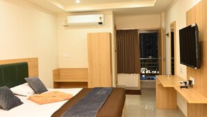 Habitación de hotel con cama, escritorio, televisión, aire acondicionado y vista al exterior.