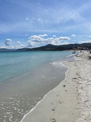 A beach with clear water, sandy shore, and distant hills. - T2 sea and mountain view, large terrace ☀️ with swimming pool - 5 mn des Plages 🏖️ (L'Île-Rousse)