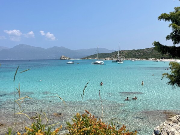 Eine Küstenlandschaft mit klarem türkisblauem Wasser, Booten und felsigem Gelände.