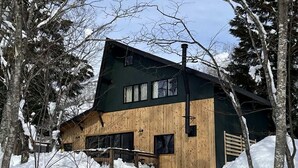 A cabin with a wooden exterior, large windows, and a chimney. - Walk to Tsugaike Ski Resort 200m. Floor heating, driveway heating, cosy & unique (Otari)