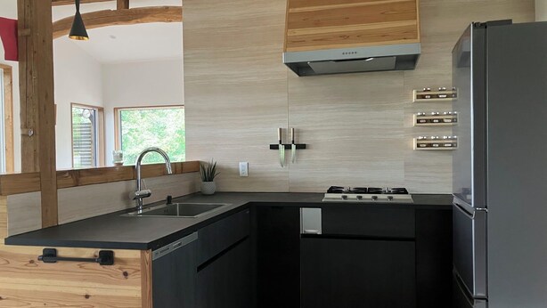 A modern kitchen with a wooden accent wall, a built-in stove, and a refrigerator. - Walk to Tsugaike Ski Resort 200m. Floor heating, driveway heating, cosy & unique (Otari)