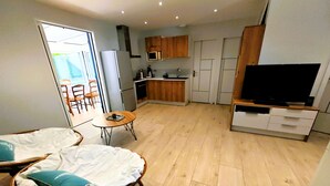 A compact living space with a dining area, kitchenette, and a TV. - La Pause Jardaise near beaches (Jard-sur-Mer)