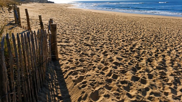 A sandy beach with a wooden fence and ocean waves. - La Pause Jardaise near beaches (Jard-sur-Mer)
