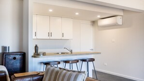 Una cocina moderna con armarios blancos, una encimera y un taburete de bar.