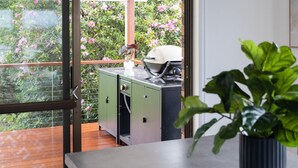 Un balcón con vistas a flores rosadas, un armario verde y una planta en maceta.