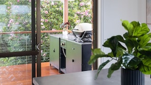 Ein Balkon mit Blick auf rosa Blumen, einem grünen Schrank und einem Blumentopf.