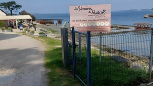 Ein Küstenanwesen mit einem Schild, einem eingezäunten Bereich und Blick auf das Meer.