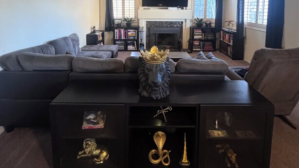 A living room with a sectional sofa, a fireplace, a television, and decorative items on a coffee table.