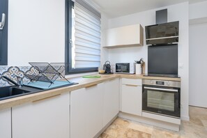 Uma cozinha moderna com forno embutido, micro-ondas e janela com persianas.