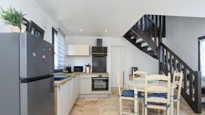 A modern kitchen with a refrigerator, microwave, oven, and dining table with chairs. - Ker Marin - Maison Le Refuge Des Marées: terrace, garden & Wi-Fi (Sarzeau)
