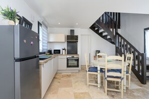 Uma cozinha moderna com frigorífico, micro-ondas, forno e mesa de jantar com cadeiras.
