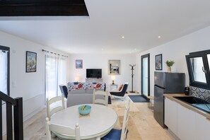 A compact kitchen with a dining area, a TV, and a refrigerator. - Ker Marin - Maison Le Refuge Des Marées: terrace, garden & Wi-Fi (Sarzeau)