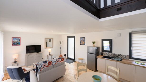 A modern kitchen with a refrigerator, stove, and sink. There is a dining table with chairs and a sofa in the living area. - Ker Marin - Maison Le Refuge Des Marées: terrace, garden & Wi-Fi (Sarzeau)