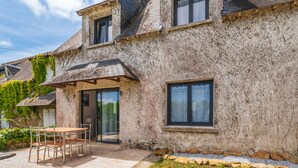 A two-story building with a stone facade, a covered patio with a table and chairs, and a window with a view. - Ker Marin - Maison Le Refuge Des Marées: terrace, garden & Wi-Fi (Sarzeau)