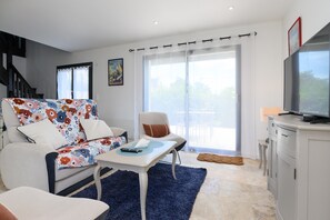 A living room with a sofa, a coffee table, a TV, and a staircase. - Ker Marin - Maison Le Refuge Des Marées: terrace, garden & Wi-Fi (Sarzeau)