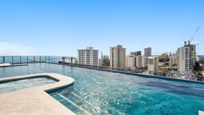 A rooftop infinity pool with a cityscape view, surrounded by high-rise buildings. - The Coastal Luxe Haven, Coolangatta (Gold Coast)