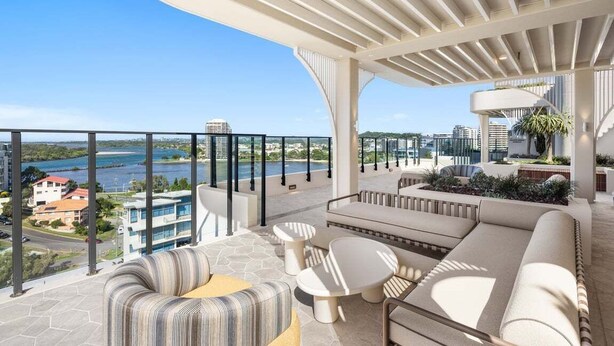 A balcony with a view of a body of water and buildings, furnished with sofas and tables. - The Coastal Luxe Haven, Coolangatta (Gold Coast)