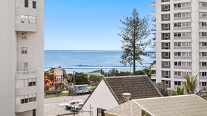A view of a coastal area with a beach, a tall building, and a playground. - The Coastal Luxe Haven, Coolangatta (Gold Coast)