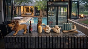 Una mesa de madera con una escultura de león, una botella de vino, velas y calaveras.