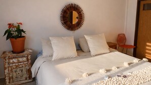 Un dormitori amb un llit, almoines, un rellotge de paret, una planta en test i una cadira.
