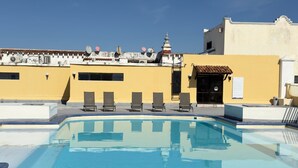 Una piscina amb gandules, un edifici de façana groga i una construcció de tipus pagoda.