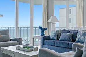 Un balcon avec vue sur la mer, un canapé agrémenté de coussins à motifs et une table avec un plateau.