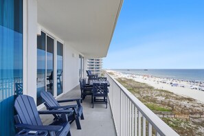 Un balcon avec vue sur la plage, des sièges d’extérieur et une rambarde.