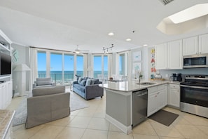 A modern kitchen with a central island, white cabinetry, and a view to the sea. - NEW LISTING!!! Lighthouse #418 Gulf Front w/HUGE Corner Balcony! (Gulf Shores)