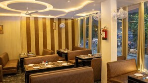 Un restaurant avec des banquettes et des tables, un ventilateur de plafond et un extincteur.