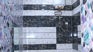 Une salle de bain comprenant des toilettes, un bidet et un lavabo, ainsi que des carreaux de marbre et un chauffe-eau.