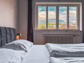Ein Schlafzimmer mit Bett, Fenster mit Bergblick und Heizkörper.