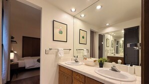 Un baño moderno con dos lavamanos, un espejo grande y muebles de madera.