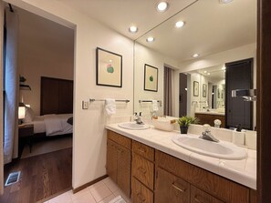 A modern bathroom with two sinks, a large mirror, and wooden cabinetry.