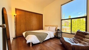 Un dormitorio con cama, armario de madera, ventana con vistas y sofá de cuero marrón.