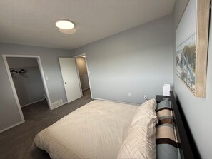 A bedroom with a bed, a door leading to a closet, and a hallway. - 3BR, Entire townhome | Parking | Near QE2, shopping malls | 10min to YEG airport (Leduc)