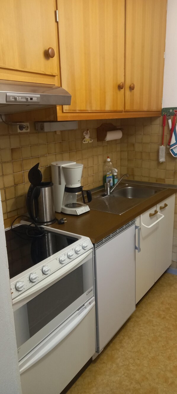 Eine kleine Küche mit Herd, Backofen, Kaffeemaschine und Spüle.