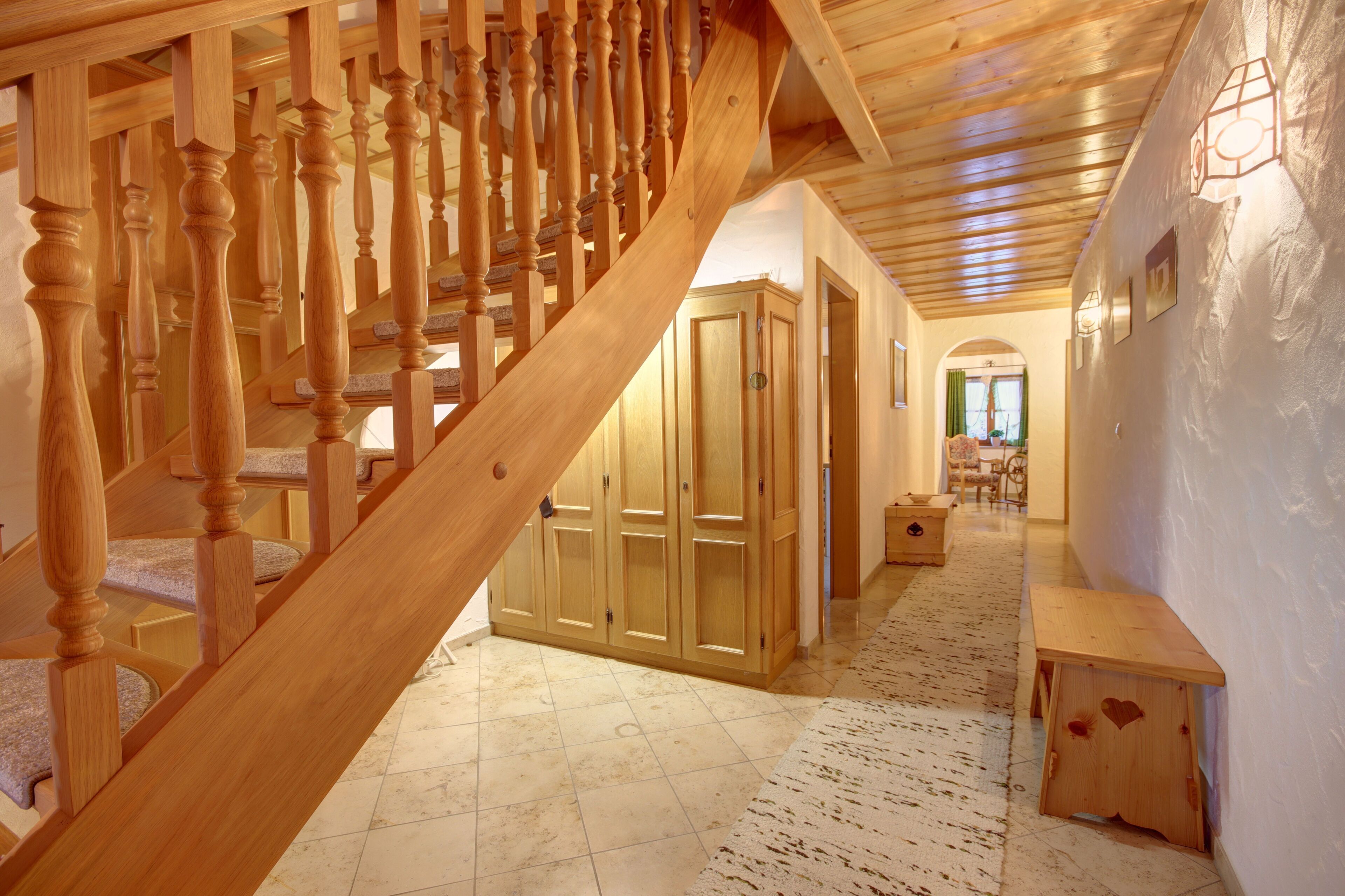 A wooden staircase leading to a room with a large wardrobe and a bench.