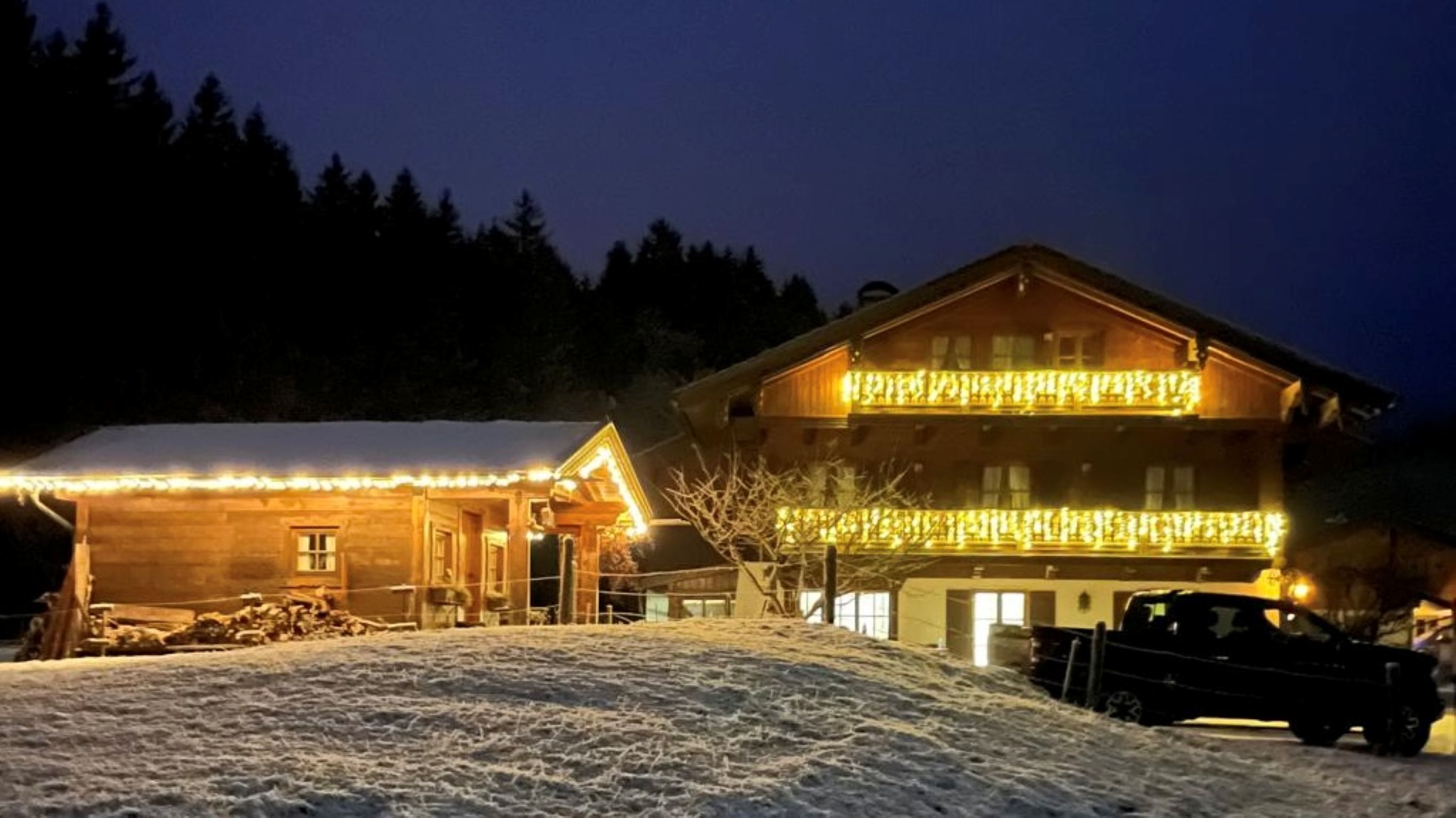 A wooden chalet with a balcony and snow-covered ground.