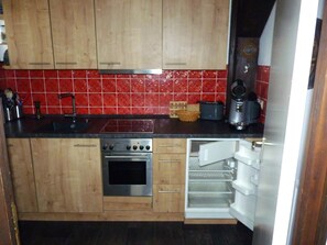 Una cucina con mobili in legno, forno in acciaio inossidabile, tostapane e frigorifero.