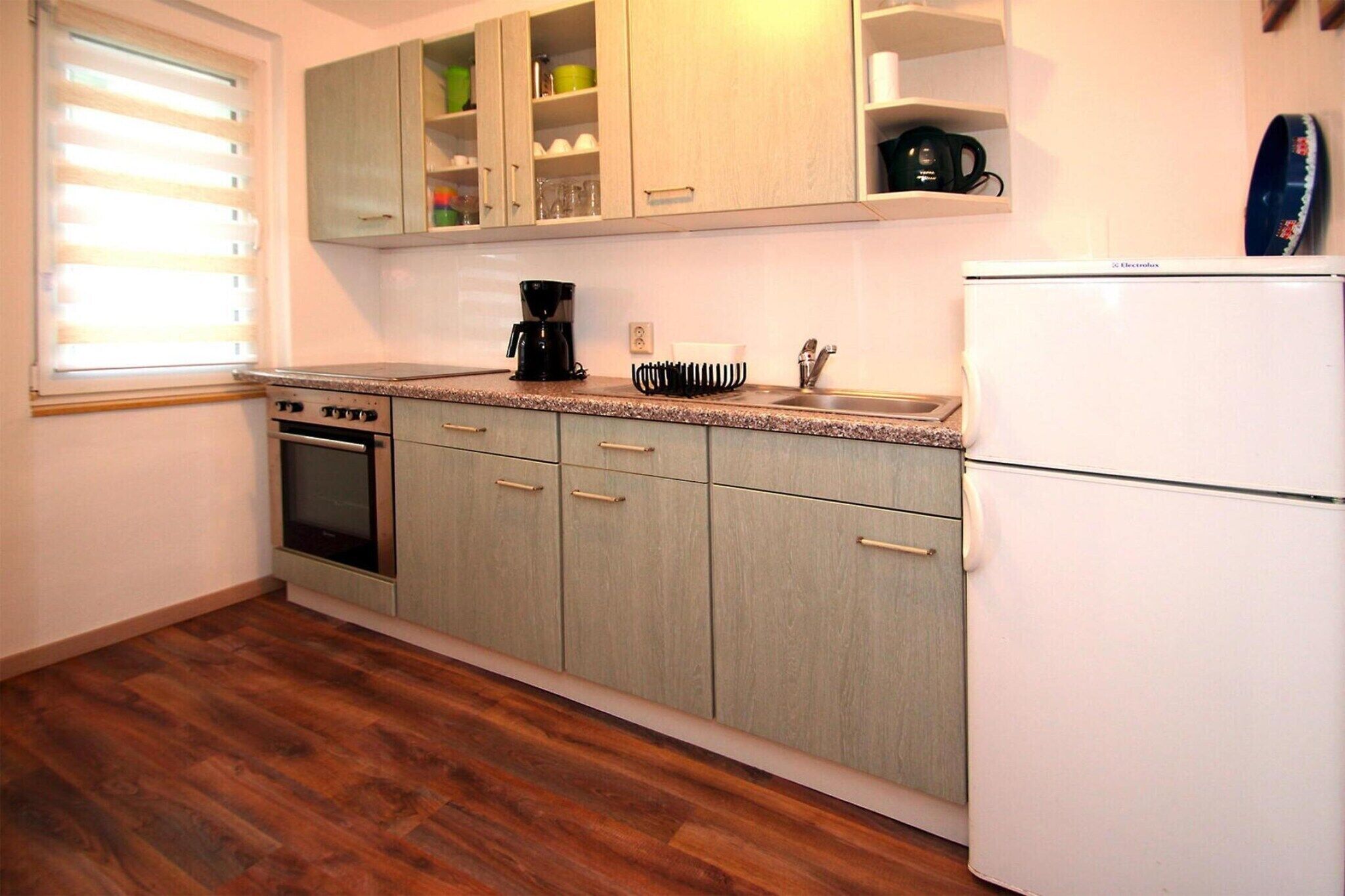 A kitchen with wooden cabinets, a stove, a coffee maker, and a refrigerator.