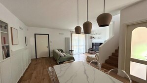 En modern inredning med ett matområde, en soffa och en trappa.