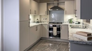 Eine moderne Küche mit eingebauten Geräten, einer Marmorarbeitsplatte und einer Edelstahl-Dunstabzugshaube.