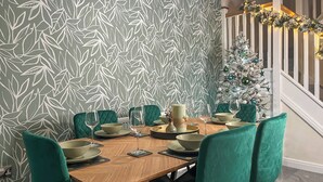 Ein Essbereich mit einem gemusterten Wandpapier, einem Weihnachtsbaum und grün gepolsterten Sesseln.